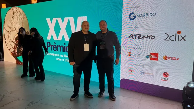Dos integrantes de Hosanna frente al panel del XXVI Prêmio ABT, junto a los patrocinadores